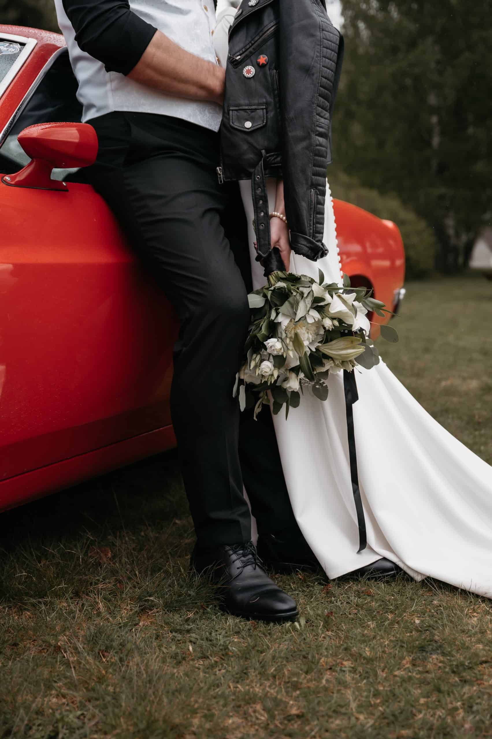 Brudepar med blomster foran en rød bil i Hønefoss.