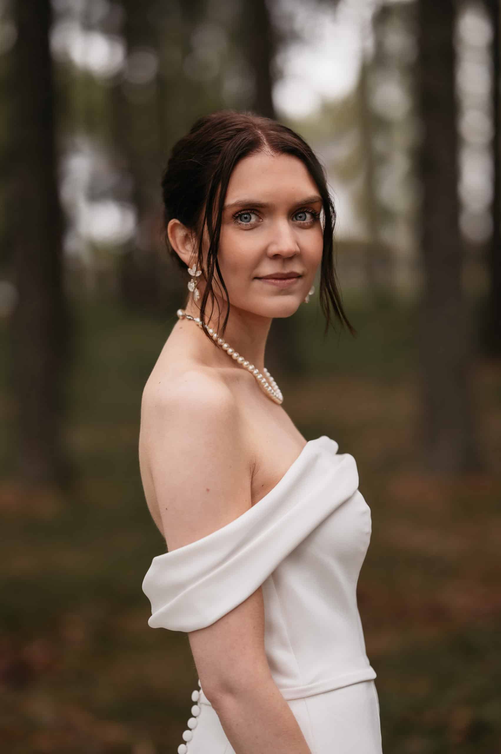 Portrett av en kvinne i brudekjole i skoglandskap.
