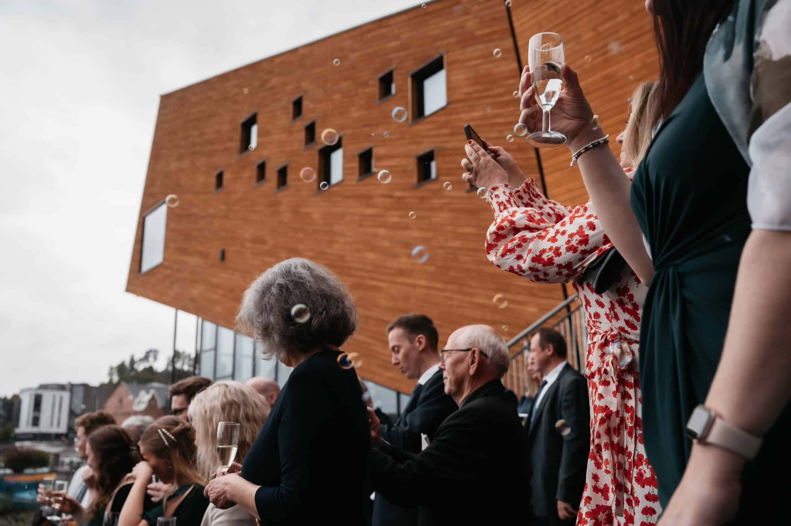 Gjestene feirer utendørs bryllup i Hønefoss med champagne og festlig stemning.