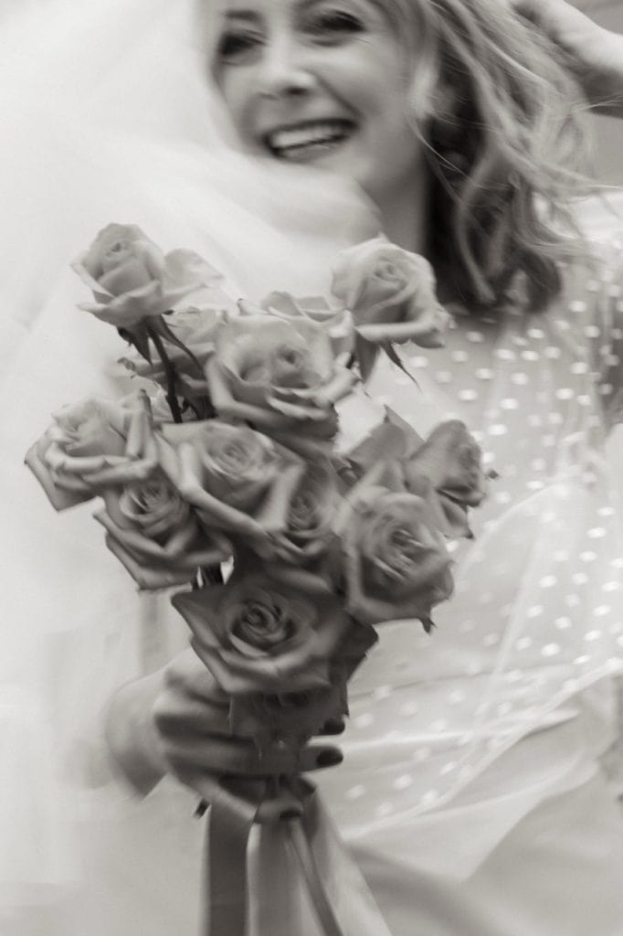 Kvinne med blomstertopp holder en stor bukett med rosa roser.