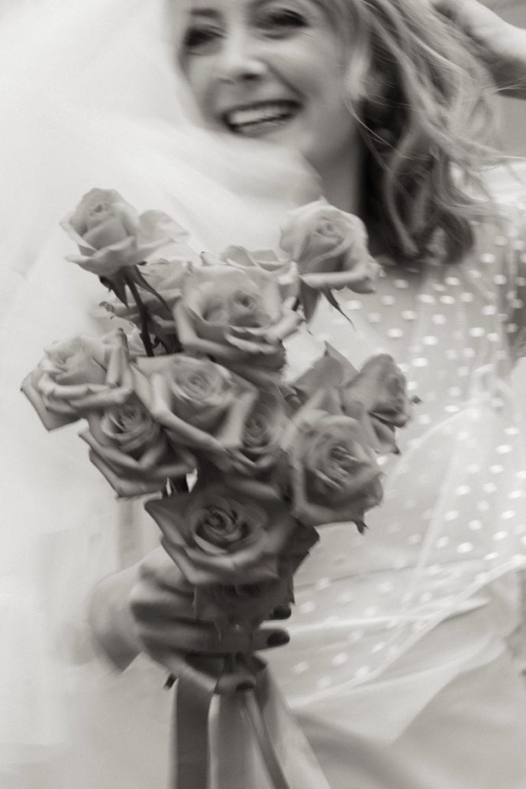 Kvinne med blomstertopp holder en stor bukett med rosa roser.