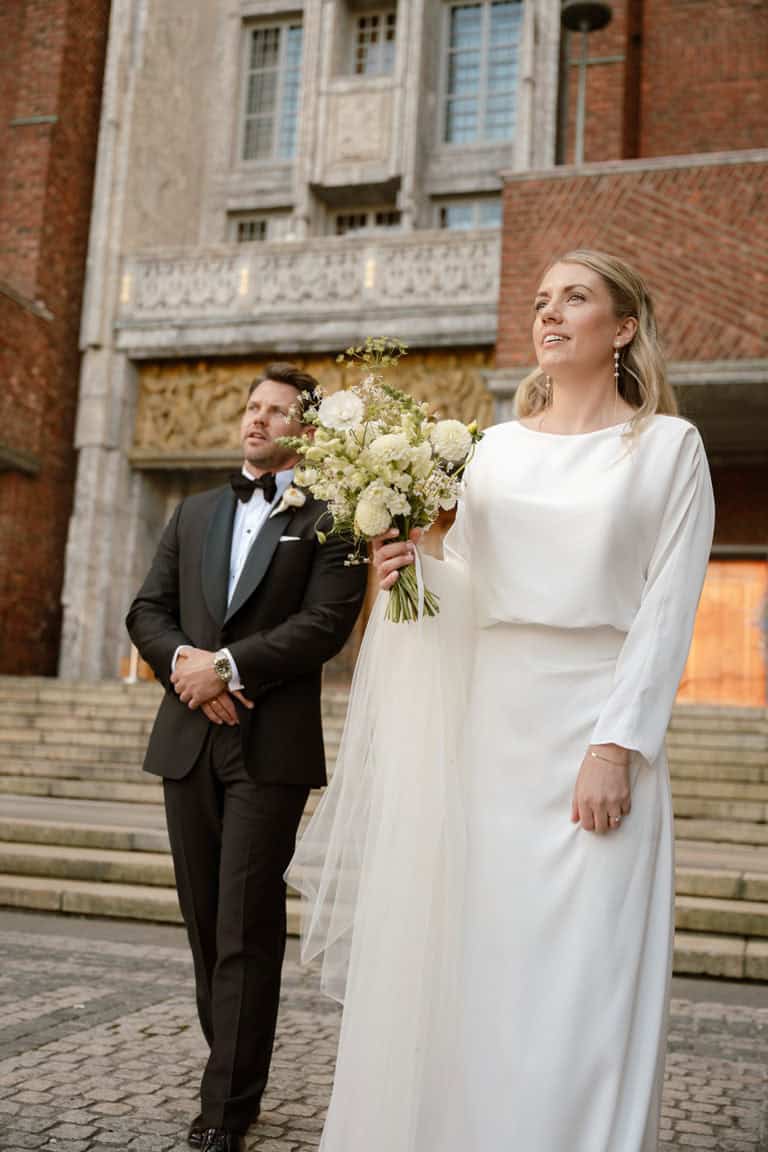Bryllupsbilde av brud og brudgom foran historisk bygning i Oslo.