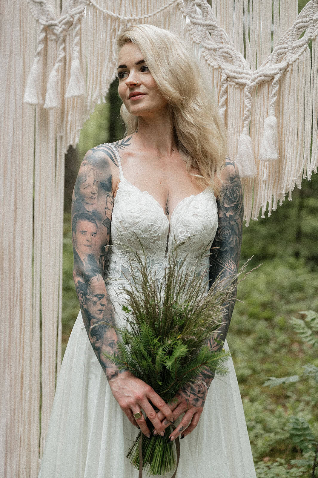 Kvinne med tatoveringer i brunt og hvitt brudekjole med blomsterbukett.