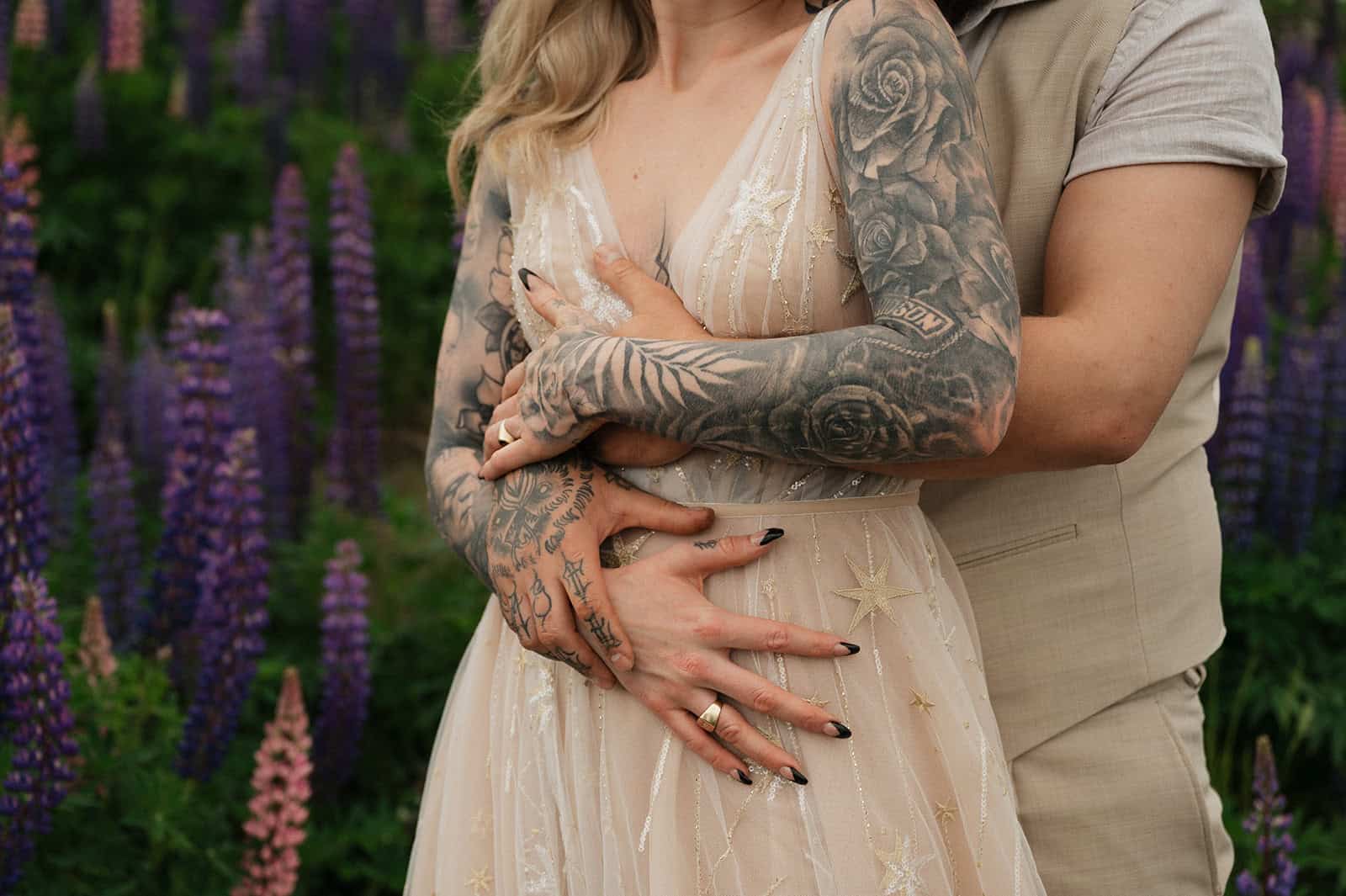 Nærbilde av et par med tatoveringer i en blomsterhage.