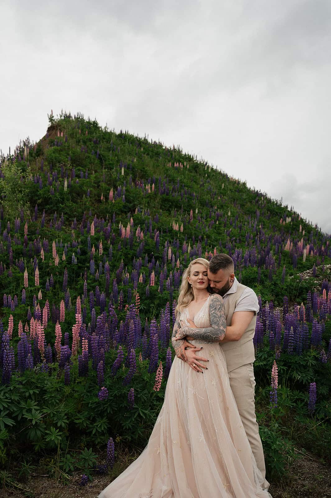 Par romantisk par foran blomstrende fjell med lavendel og villblomster.